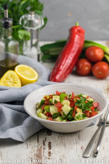 Eine Schüssel türkischer Coban-Salat vor den Zutaten Paprika Tomate Gurke