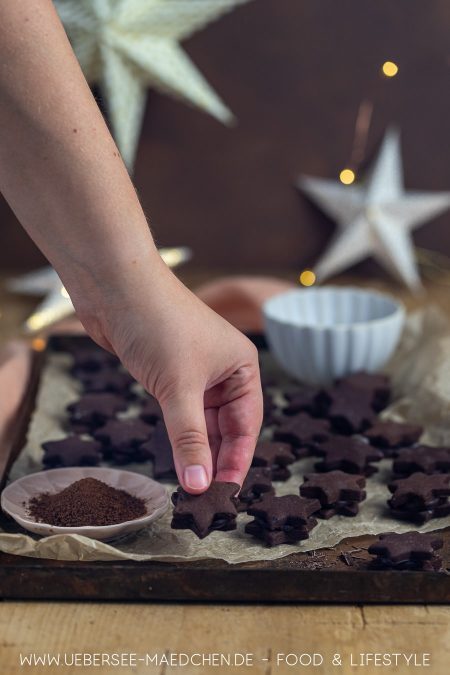 Hand greift nach Schokoladen-Plätzchen mit Espresso-Ganache