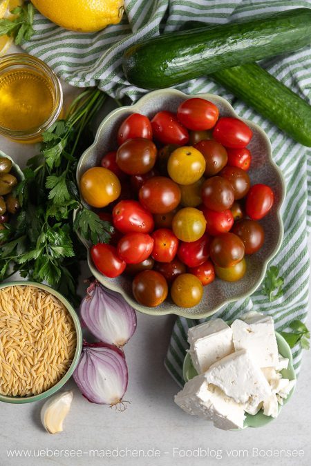 Zutaten für griechischer Nudelsalat mit Orzo Tomaten Gurken Zwiebeln Oliven Feta