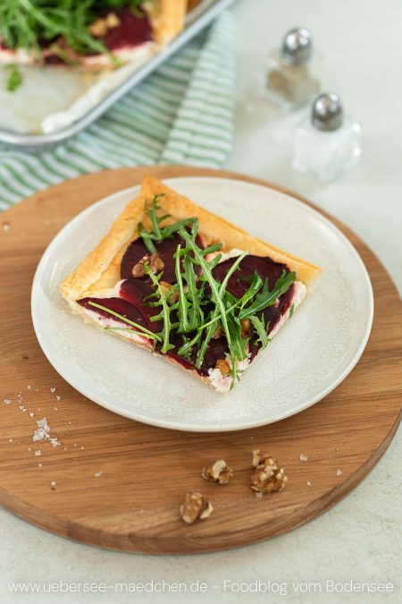 Ein Stück Rote-Bete-Tarte aus Blätterteig mit Ziegenkäse Rucola