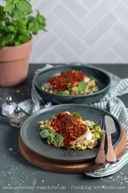 Zwei Teller mit Nudeln, weißem Fisch und würziger Kruste